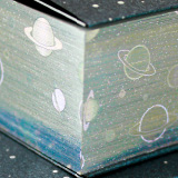 『宇宙柄』の箔が天・地・小口に輝く「天金加工」が使用されています。カバーの紺色から覗く光り輝く宇宙の圧倒的な存在感が、作品を唯一無二の特別な一冊にしています！